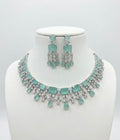 Jewelry set with necklace and earrings featuring light blue stones on a white background