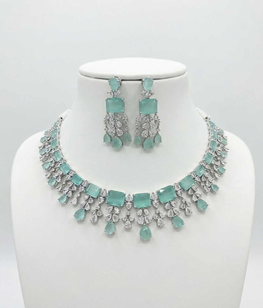 Jewelry set with necklace and earrings featuring light blue stones on a white background
